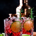 Refreshing drink with cranberries, ice and rosemary on wooden background, red cocktail, copy space