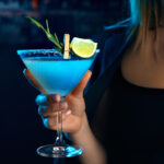Young woman in a bar or club having fun - in the background her bar, focus on the glass she is holding in her hand, close up